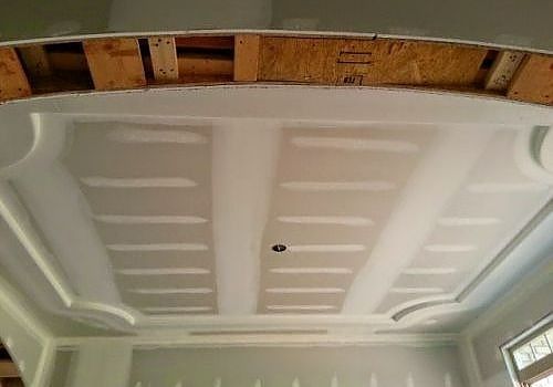 White car trunk interior with the hood open, showing molded paneling and a small black hole in the center
