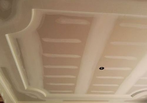 White tray ceiling with recessed rectangular panels and a small central light fixture.
