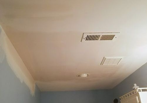Ceiling with two vents and a smoke detector in a room with blue walls