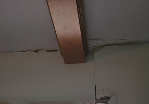 Ceiling with a wooden beam and a visible crack along the seam