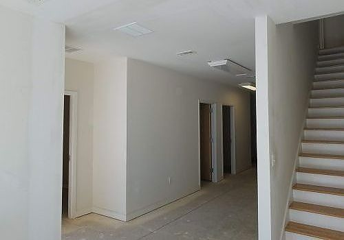 Empty white hallway with stairs on the right and doorways along the left wall
