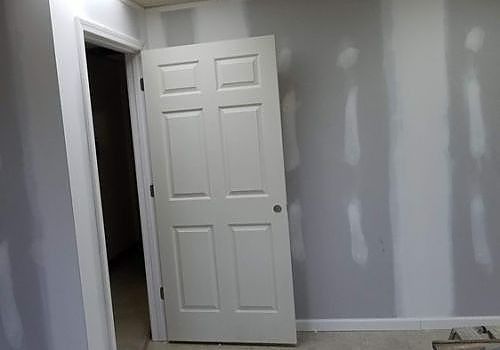 Empty room with gray walls, white trim, and a white door standing open