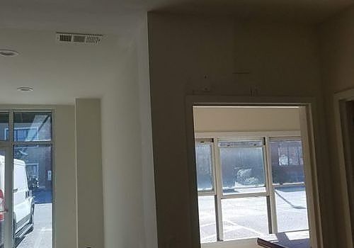 Empty interior room with white walls and large windows letting in bright sunlight.