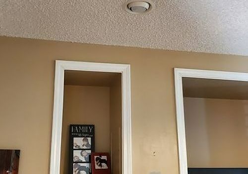 Tan wall with two white-framed recessed wall niches, one holding a small family photo display.