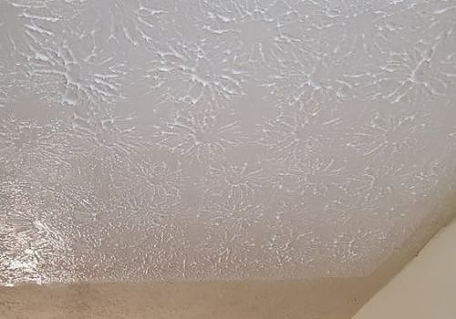 Textured white ceiling and beige wall corner indoors