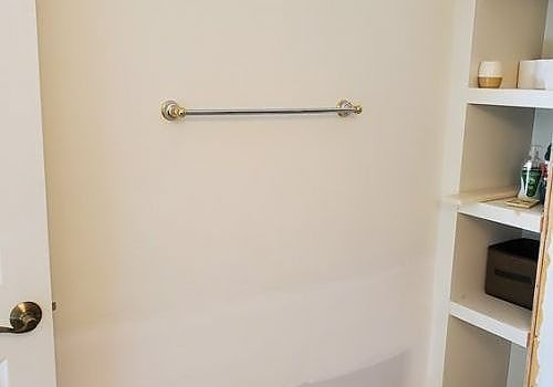 Bathroom wall with towel bar and built-in shelves containing toiletries