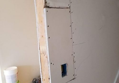 Partially finished wall with drywall patch and exposed electrical box