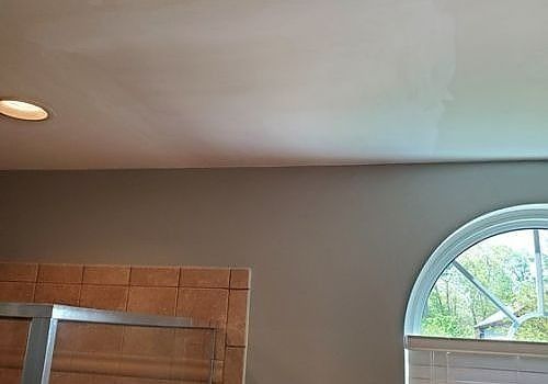 Living room ceiling with recessed light, brown wall, tiled fireplace edge, and arched window with blinds