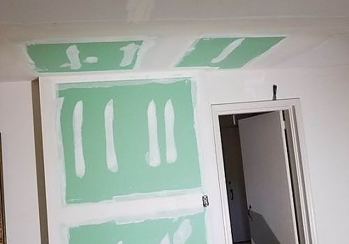 Mint-green drywall patches around a doorway during interior renovation.
