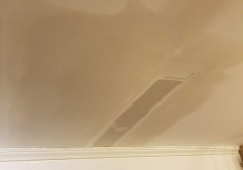 Beige ceiling with a long patched crack or repaired section near the crown molding