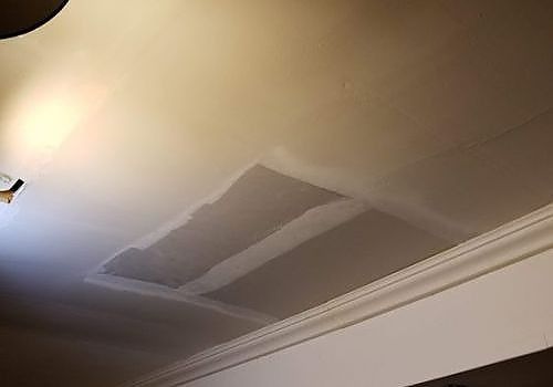 Ceiling with a gray patch or repair area near a corner and light fixture nearby