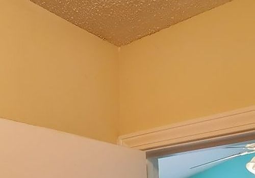 Beige interior corner with textured ceiling and the top of a doorway