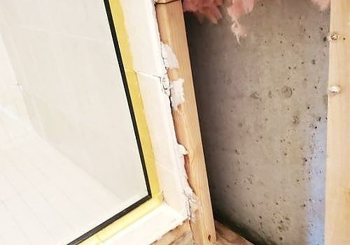 Partially finished doorway with exposed wood, white trim, and a concrete wall inside