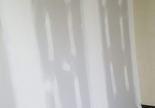 White wall with vertical paint or drywall repair patches running down the surface.