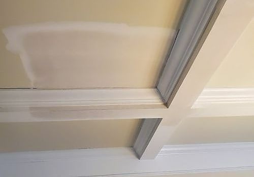 Ceiling with white crown molding and gray trim around a recessed panel.