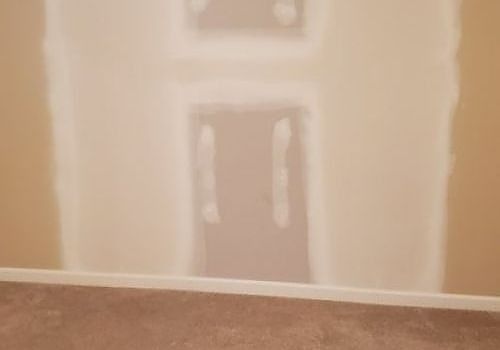 Unfinished wall with a covered doorway cutout above a carpeted floor