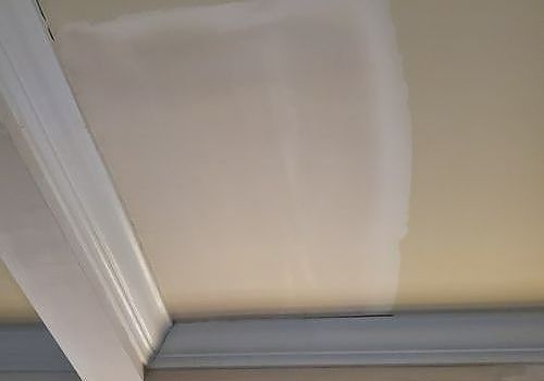 Close-up of a white ceiling panel with a seam and crown molding corner.