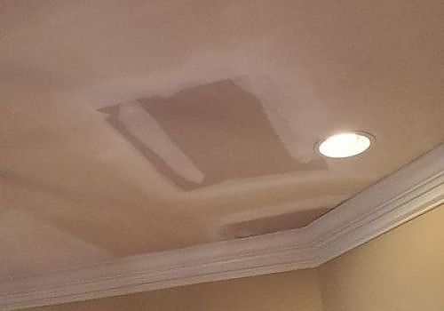 Ceiling with a large water stain and patch near a recessed light.