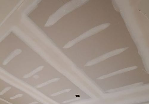 Unfinished drywall ceiling with taped seams and a small recessed light opening