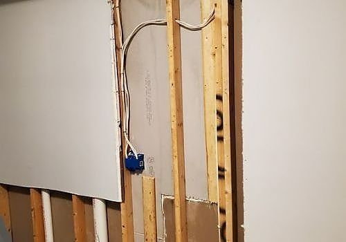 Exposed wall studs with electrical wiring and a blue outlet box during renovation