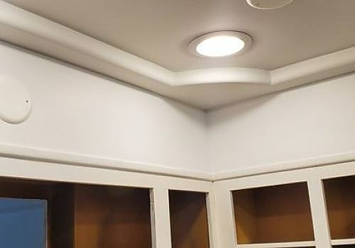 White ceiling with recessed lights above a corner wall and cabinets in a room
