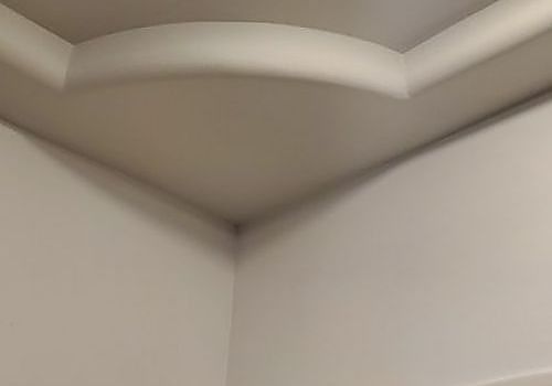 White room ceiling corner with a recessed soffit and shadowed seam at the junction of two walls