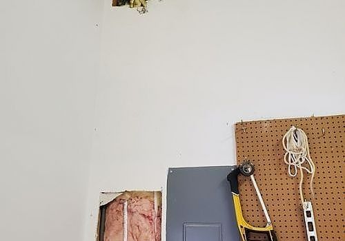 White wall with a pegboard holding tools and a gray cabinet in a garage or workshop corner
