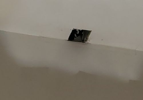 Damaged ceiling with a small hole exposing dark interior