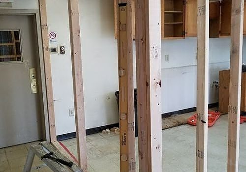 Interior renovation with exposed wall studs, a doorway, and construction tools on the floor