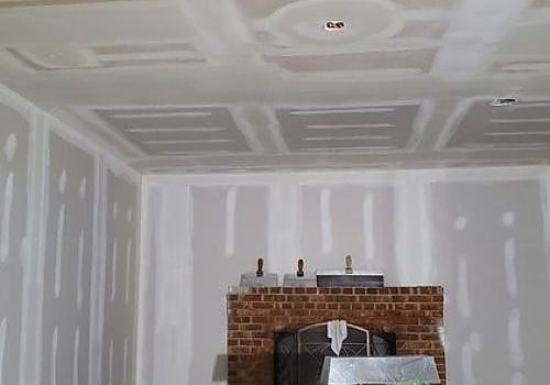 Unfinished room with drywall seams and a brick fireplace under construction