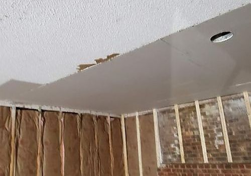 Partially unfinished ceiling with visible water damage and exposed wall framing inside a room
