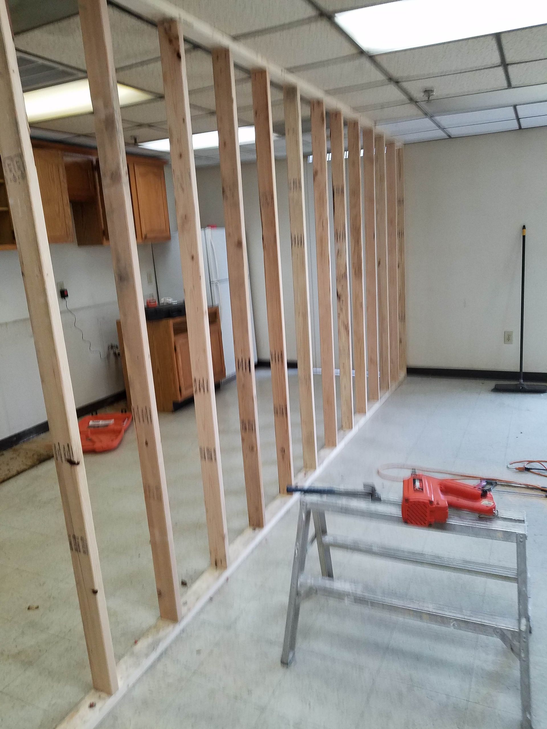 Partially framed interior with exposed wooden studs and a small workbench in the foreground