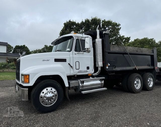 A white dump truck is parked in a gravel lot.