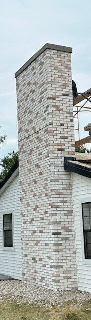 A white brick chimney on the side of a house.