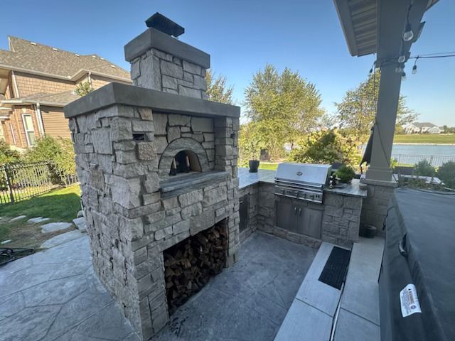 A stone fireplace with a pizza oven in the backyard of a house.