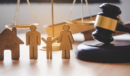 Wooden family figures, house, scales, and gavel symbolizing family law and home.