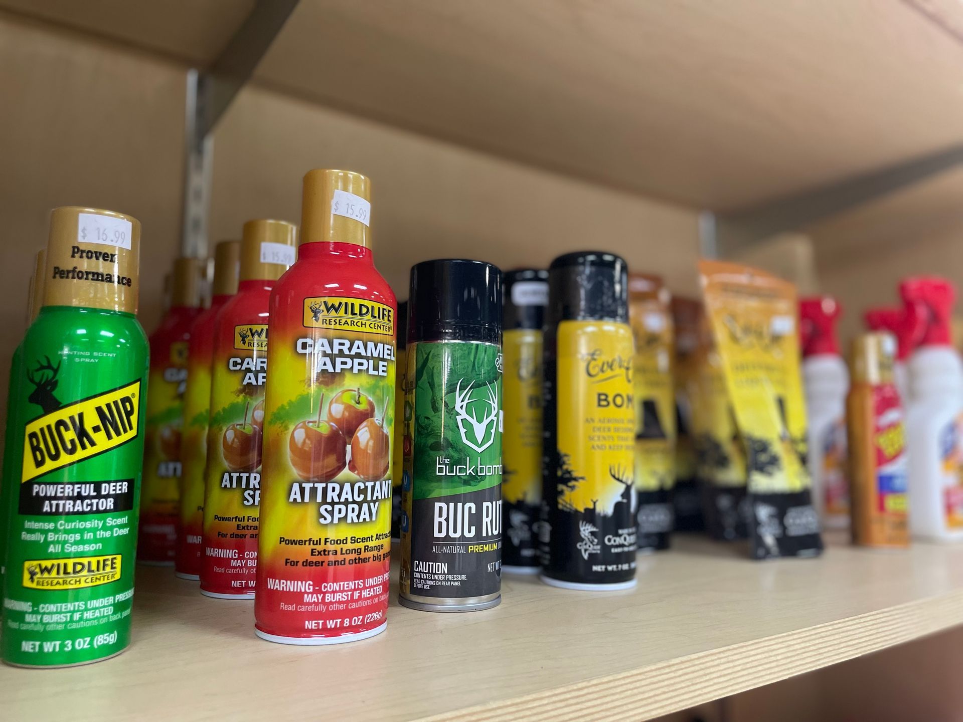Deer attractant sprays and other hunting products on a shelf in a store.