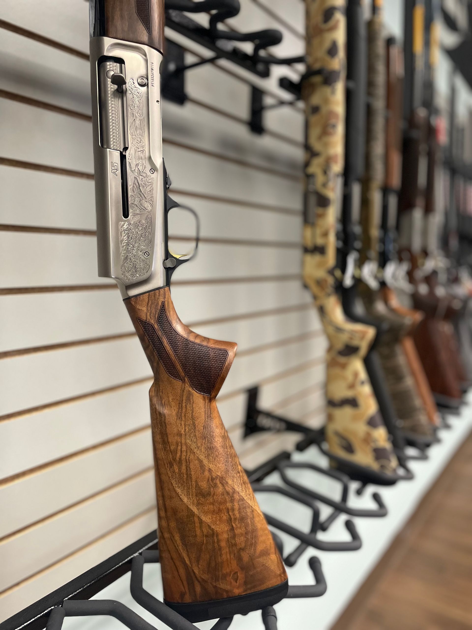 A row of shotguns hanging on a wall in a store