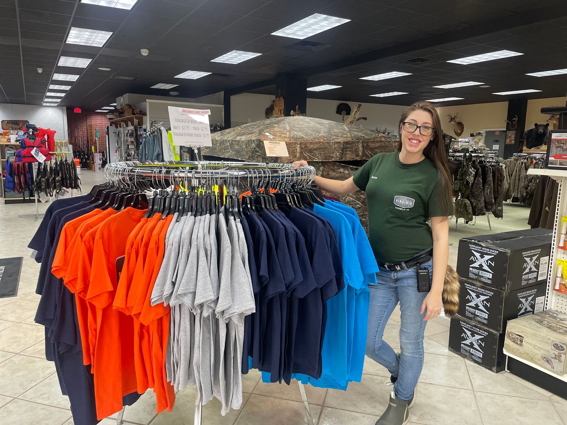 A woman is standing in front of a rack of shirts in a store.