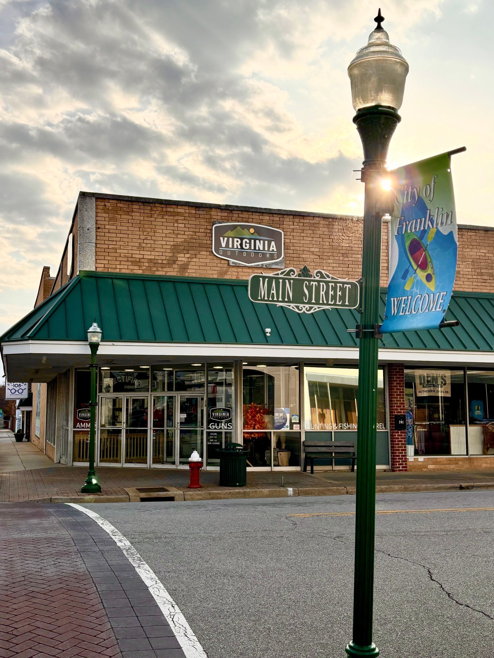 Storefront on Main Street with green awning, brick facade, and street sign, under cloudy sky.