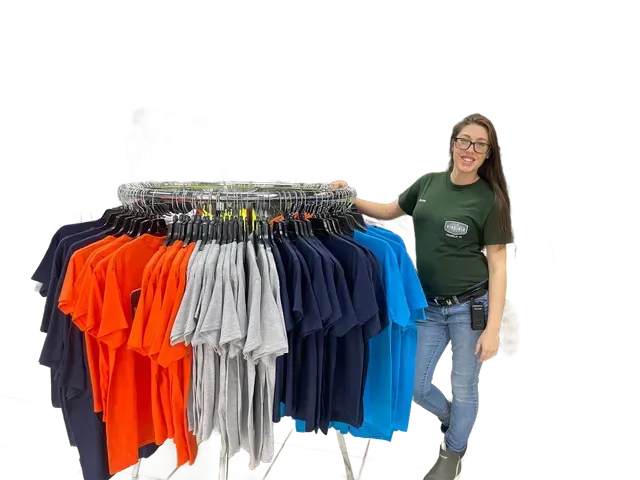 A woman is standing in front of a rack of shirts in a store.
