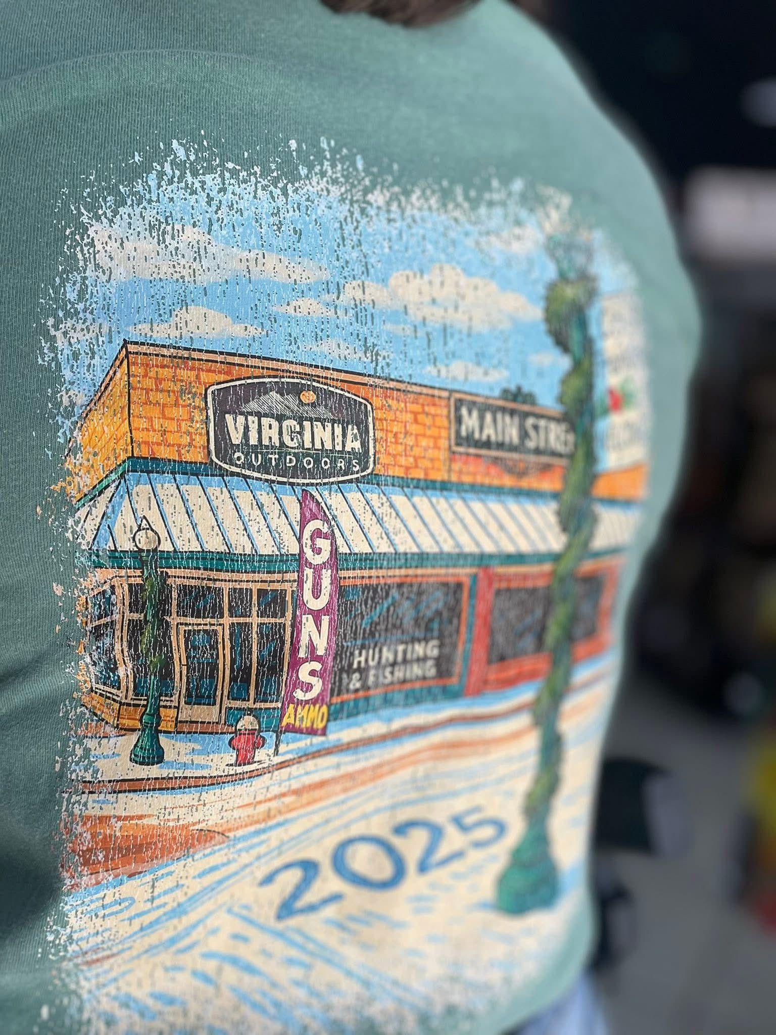 Green t-shirt with a colorful illustration of a Main Street building. It says Vineyard, Gifts, and 2025.
