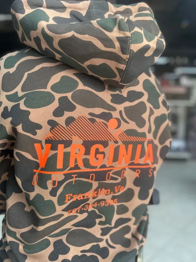 Camouflage hoodie with orange “VIRGINIA” text on the back, worn outdoors