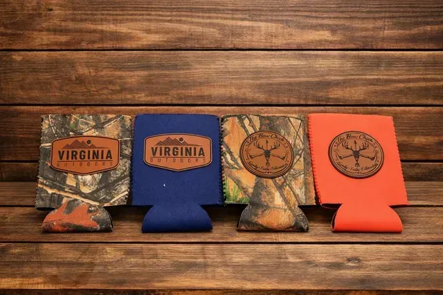 Four Virginia-themed foldable drink coolers in camouflage, blue, tan, and orange on a wooden surface