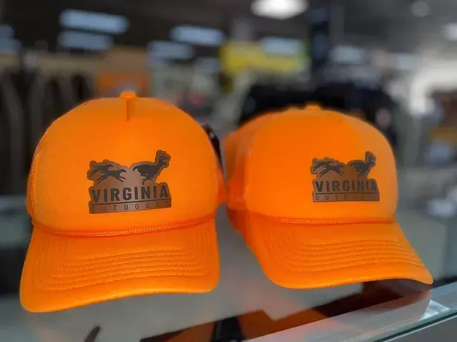 Two bright orange Virginia baseball caps displayed side by side on a shelf