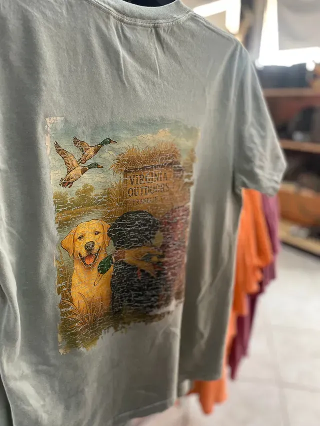 Gray T-shirt with a dog, bird, and printed quote graphic hanging on a rack