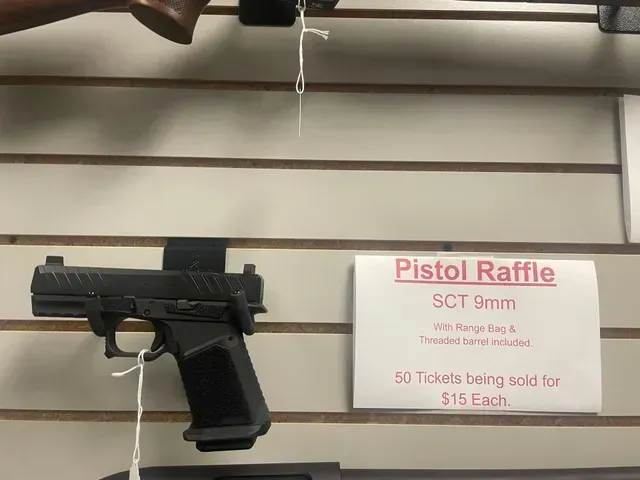 Black pistol displayed on a store wall beside a “Pistol Raffle” sign