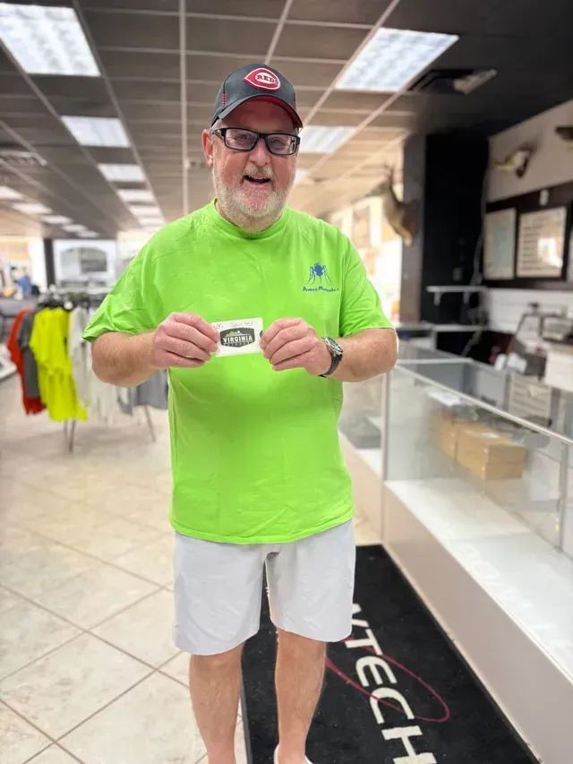 Man in neon green shirt holding a card, standing inside a store with products and bright lighting.