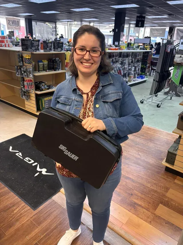 Smiling person in a denim jacket holding a Pioneer case in an electronics store.