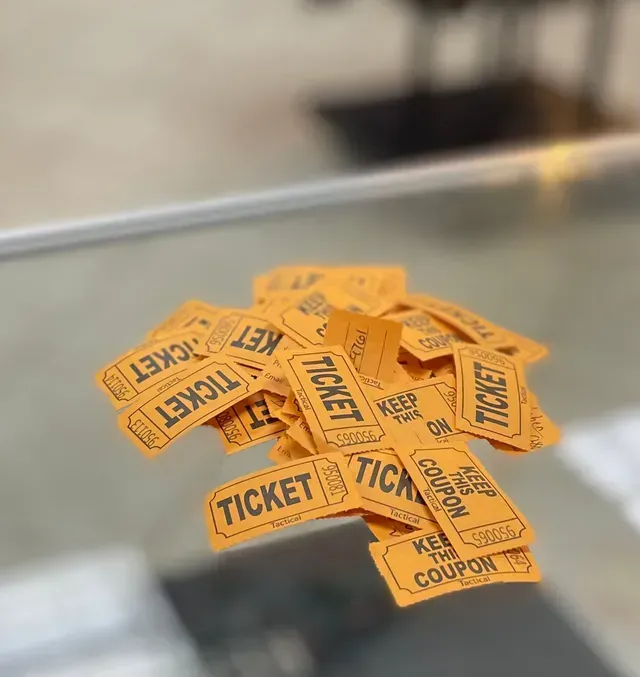 Pile of orange ticket stubs on a glass counter.